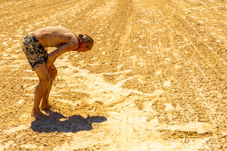 Male tourist traveling man with long hair is having a beach sand peeling on his skin on the Mexican Caribbean beach in Playa del Carmen Quintana Roo Mexico.の写真素材