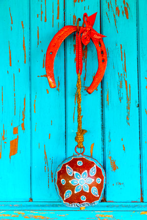 Hanging cowbell and horse hooves horseshoes on the turquoise blue door.の写真素材