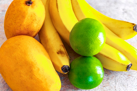 Ripe juicy yellow mangoes bananas and lime limes fruit fruits on the table in Playa del Carmen Quintana Roo Mexico.の写真素材