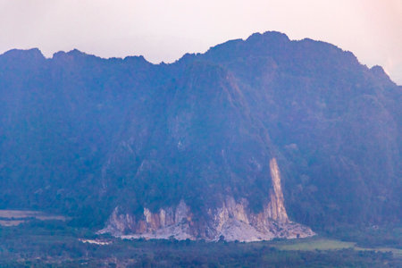 Mountain peak landscape with tropical forest jungle hills rocks and amazing colorful golden sunset sunrise in Vang Vieng Vientiane Province Laos in Southeastasia Asia.の写真素材