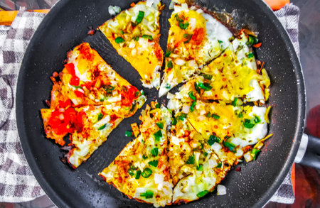 Fried eggs like pizza with tomato onion garlic and greens in Playa del Carmen Quintana Roo Mexico.