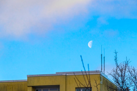 Yellow gray high rise building in winter landscape with moon and blue cloudy sky in Leherheide Bremerhaven Bremen Germany.の写真素材