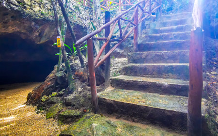 Beautiful Cenote Park Yaxmuul stairs steps into the cave with limestone rocks turquoise blue green water and nature jungle around it in Tulum Quintana Roo Mexico.の写真素材