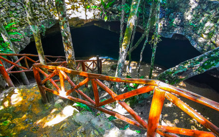 Beautiful Cenote Park Yaxmuul wooden stairs steps into the cave with limestone rocks turquoise blue...