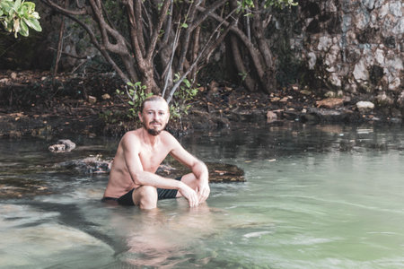 Man inside of a dark cave cenote with fresh water in Playa del Carmen Quintana Roo Mexico.の写真素材