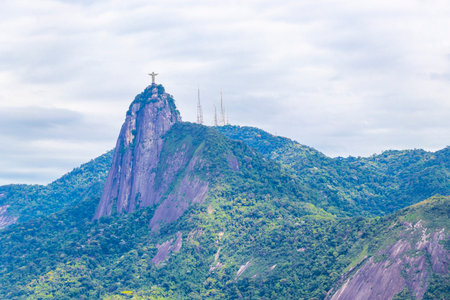Christ the Redeemer Cristo Redentor on Corcovado mountain hill rock tropical forest and blue cloudy...