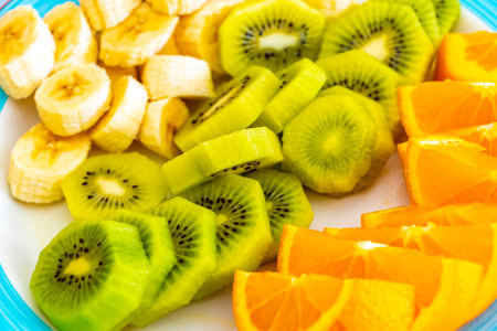 Sliced oranges, kiwi and bananas on a plate.の写真素材