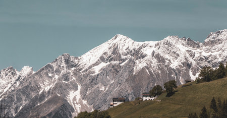 Mountain and alpine hill landscape mountains rocks and peaks panorama of Lechtal alps with green field meadow village forest huts snow and blue sky in Fliess Landeck Tyrol Austria.の写真素材