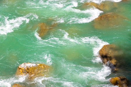 Turquoise blue and green river steam and waterfall Inn with stones rocks grass trees nature between...