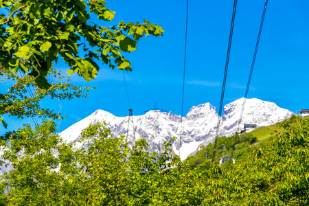Mountain and alpine hill landscape mountains rocks and peaks panorama of Lechtal alps with green fields meadows snow and blue sky behind forest tree trees in Fliess Landeck Tyrol Austria.の写真素材