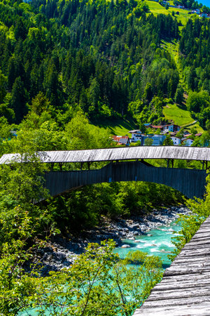 Turquoise blue and green river steam and waterfall Inn with wooden bridge stones rocks grass trees nature and mountain panorama in the Alps FlieÃ Landeck Tyrol Austria.の写真素材