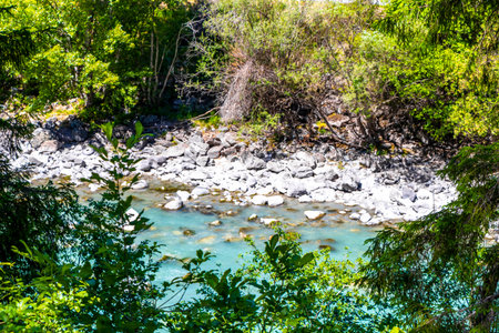 Turquoise blue and green river steam and waterfall Inn with stones rocks grass trees nature between mountains in the Alps FlieÃ Landeck Tyrol Austria.の写真素材