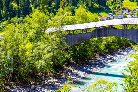 Turquoise blue and green river steam and waterfall Inn with bridge stones rocks grass trees nature and mountain panorama in the Alps FlieÃ Landeck Tyrol Austria.の写真素材
