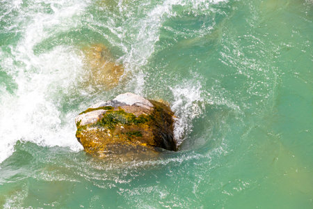 Turquoise blue and green river steam and waterfall Inn with stones rocks grass trees nature between...