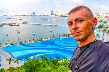Handsome Man Tourist and Traveler with the Pattaya City Bay Beach Nature Jungle Pier and Boats Panorama View in Pattaya Bang Lamung Chon Buri Thailand.の写真素材