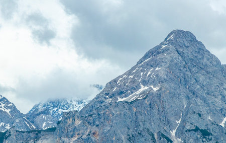 Cold panoramic view of Germanys largest mountain Zugspitze peak alpine landscape with snow rocks hills clouds and mountains in the Alps Biberwier Reutte Tyrol Austria.の写真素材