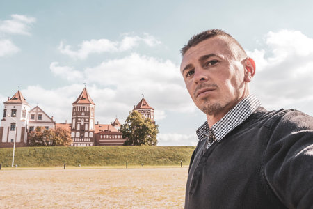 Man handsome male tourist at the Mir Castle majestic fortification fortress park and monument with blue sky in Mir Karelichy District Hrodna Region Belarus.の写真素材