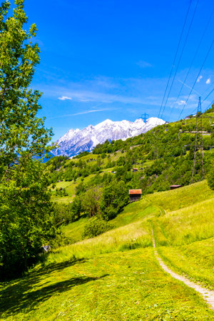 Mountain and alpine hill landscape mountains rocks and peaks panorama of Lechtal alps with green field meadow village forest huts snow and blue sky in Fliess Landeck Tyrol Austria.の写真素材