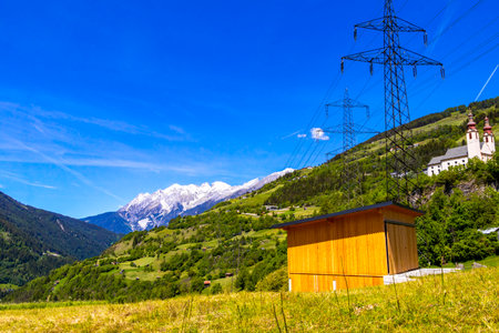 Power pole electricity pylon at mountain and alpine hill landscape mountains rocks and peaks panorama of Lechtal alps with snow nature and blue sky in the Alps Fliess Landeck Tyrol Austria.の写真素材
