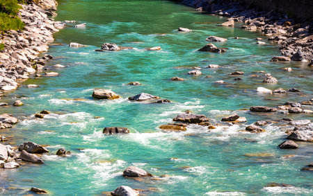 Turquoise blue and green river steam and waterfall Inn with stones rocks grass trees nature between mountains in the Alps in the alps Landeck District Landeck Tyrol Austria.の写真素材