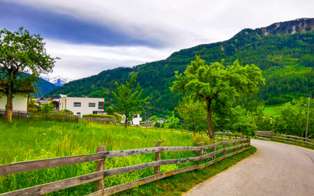 Walking path street at the mountain and alpine hill landscape mountains rocks and peaks panorama with green fields meadows village forest houses in Fliess Landeck Tyrol Austria.の写真素材