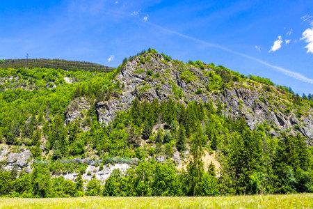 Mountain and alpine hill landscape mountains rocks and peaks panorama with green fields meadows village forest fir trees and cloudy blue sky in Fliess Landeck Tyrol Austria.の写真素材