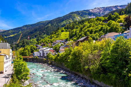 Landeck Tyrol Austria May 30, 2025 Turquoise blue and green river steam and Inn with bridge stones rocks trees nature and mountains in the Alps Landeck Tyrol Austria.の写真素材