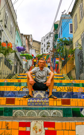 Handsome man male tourist and traveler on Escadaria Selaron the red famous stairs stair step steps staircase in Rio de Janeiro State of Rio de Janeiro Brazil.の写真素材