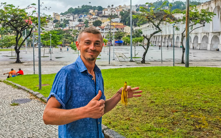 Handsome man male tourist and traveler Arcos da Lapa bridge and City Streets Panorama with arches blue cloudy sky Cars and People in Rio de Janeiro Brazil.の写真素材