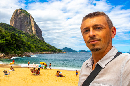 Handsome Tourist Traveler Man is Posing at the Sugarloaf Sugar Loaf Mountain Hill Rock Pao de Acucar Panorama View in the Urca Village of Rio de Janeiro Brazil.の写真素材