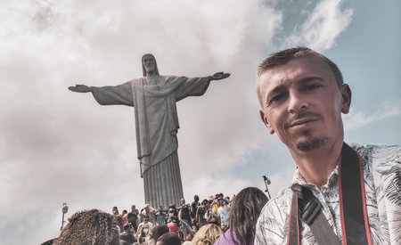 Handsome tourist traveler model and photographer at the Christ the Redeemer Cristo Redentor statue on the Corcovado mountain with blue sky panorama view in Rio de Janeiro Brazil.の写真素材