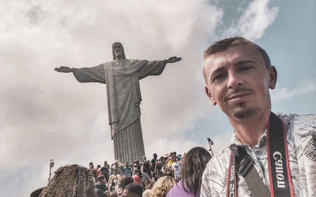Handsome tourist traveler model and photographer at the Christ the Redeemer Cristo Redentor statue on the Corcovado mountain with blue sky panorama view in Rio de Janeiro Brazil.の写真素材