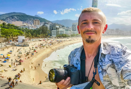 Male handsome tourist with camera takes selfie on Ipanema Beach Tropical Paradise with Blue...