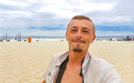 Male handsome tourist takes selfie on Copacabana Beach Tropical Paradise with Blue Turquoise Water...