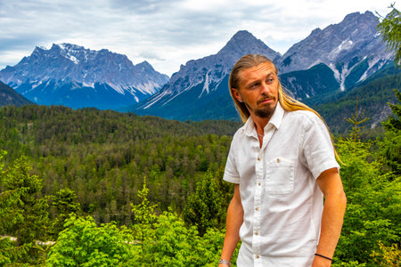 Man male tourist model at the panoramic view of Germanys largest mountain Zugspitze alpine landscape with lake forest rocks hills and mountains in the Alps Biberwier Reutte Tyrol Austria.の写真素材