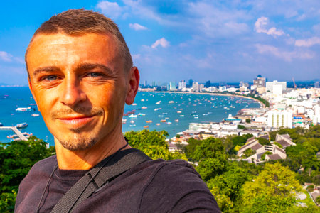 Handsome Man Tourist and Traveler with the Pattaya City Bay Beach Nature Jungle Pier and Boats Panorama View in Pattaya Bang Lamung Chon Buri Thailand.の写真素材