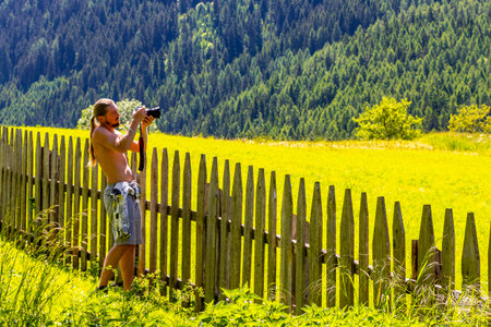 Long haired man with bare upper body photographs nature in the Alps Fliess Landeck Tyrol Austria.の写真素材