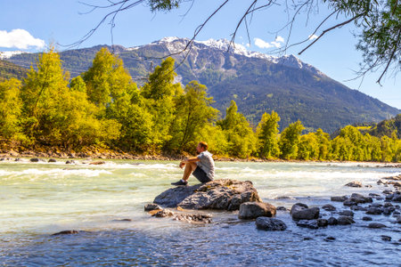 A man on the rocks by the river Inn in the Alps Zams Landeck Tyrol Austria.