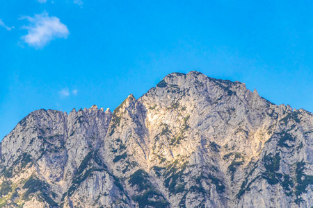 Mountain and alpine landscape with peaks, panorama, green fields, forest, nature, and blue sky in...