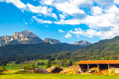 Mountain and alpine hill landscape mountains rocks and peaks panorama of alps with green field meadow village forest huts hut houses and blue sky in the Alps Salzburg Region Austria.の写真素材