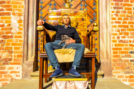Man on royal armchair and cat on his lap in Mir Hrodna Hrodsenskaja Voblasz Belarus.