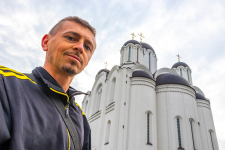 Handsome male tourist man takes selfie photo at the temple of the Icon of the Mother of God church...