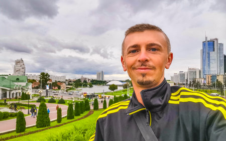 Man male tourist at the city streets with buildings skyscraper skyscrapers cityscape skyline panorama view of Minsk Belarus.の写真素材