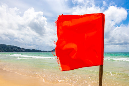 Patong Beach bay with red flag warning sign sea coast panorama view with turquoise blue clear water waves mountains palms in Patong Beach Kathu District Phuket Island Province Southern Thailand.の写真素材