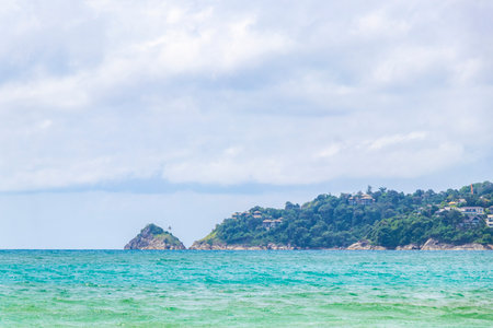 Patong Beach bay sea coast panorama view with turquoise blue clear water waves white sand and green mountains and palm trees in Patong Beach Kathu District Phuket Island Province Southern Thailand.の写真素材