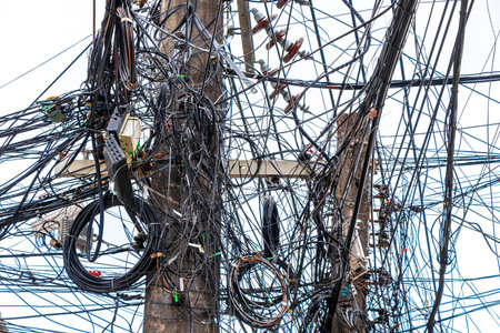 Extreme cable clutter on a power pole at transformer in the city town.