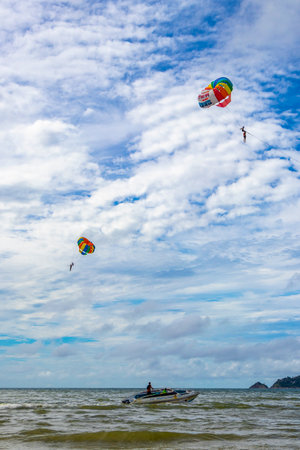 Kathu Phuket Thailand October 10, 2025 Patong Beach bay sea coast panorama view with people tourism and parasailing parachute sport activity water waves mountains and clouds in Patong Phuket Thailand.の写真素材