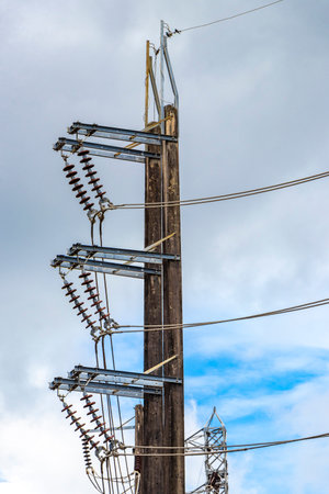 Cable clutter on a power pole at transformer in the city town with blue cloudy sky.の写真素材