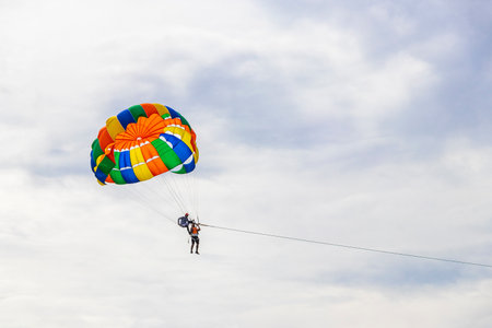 Kathu Phuket Thailand October 10, 2025 Patong Beach bay sea coast panorama view with people tourism and parasailing parachute sport activity water waves mountains and clouds in Patong Phuket Thailand.の写真素材