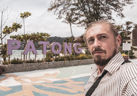 Tourist male traveler takes selfie at Patong Beach welcome name lettering letters sign signpost in Patong Kathu on Phuket island Thailand.の写真素材